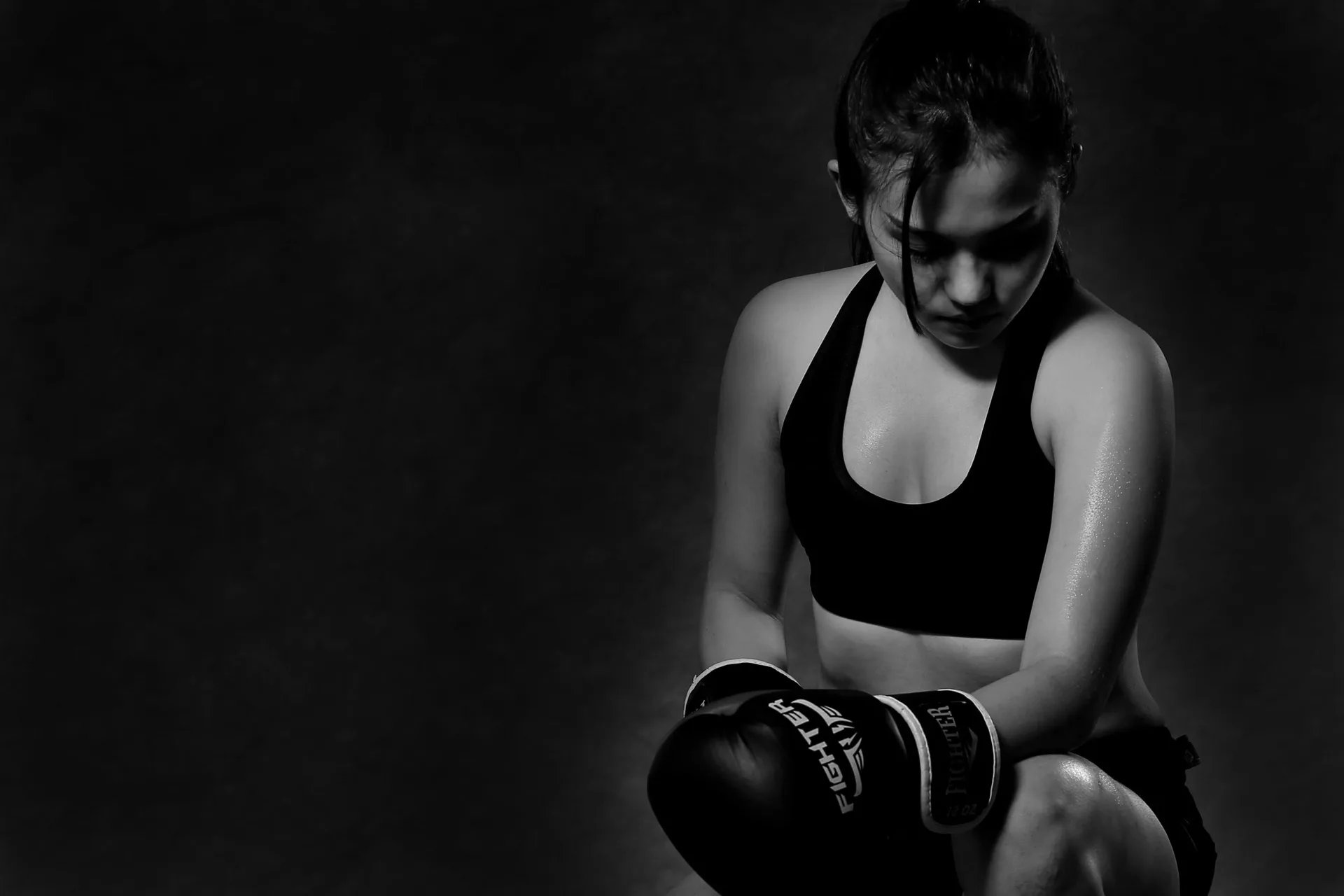 A boxer resting between rounds in low, dramatic light